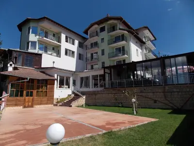 a large building with a basketball court in front of it at Хотел ПАНОРАМА ДОСПАТ in Dospat