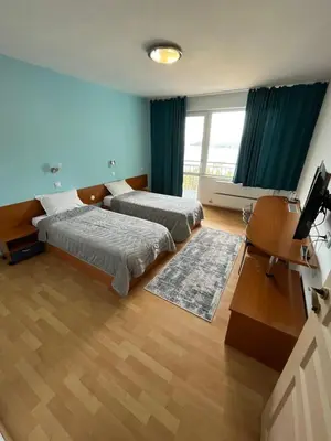 a hotel room with two beds and a television at Хотел ПАНОРАМА ДОСПАТ in Dospat