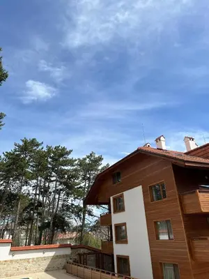 a brown and white building with trees in the background at Апартамент Ренета Apartment Reneta in Velingrad