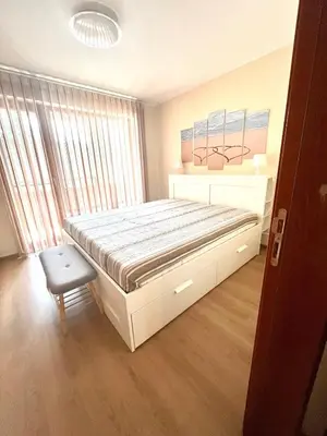 a bedroom with a large bed and a chair at Апартамент Ренета Apartment Reneta in Velingrad