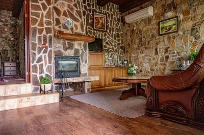 a living room with a stone wall with a television at Safari Village Velingrad in Velingrad