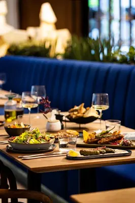 a wooden table with plates of food and wine glasses at Juno Hotel Sofia, a Member of Design Hotels in Sofia