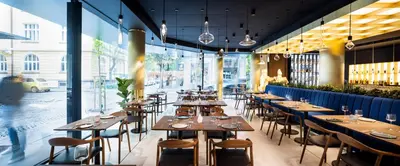 a restaurant with wooden tables and chairs and windows at Juno Hotel Sofia, a Member of Design Hotels in Sofia