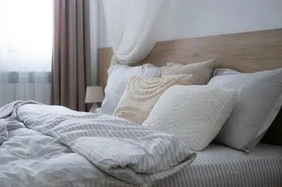 a bed with white sheets and pillows on it at Лиловата Къща in Kalofer