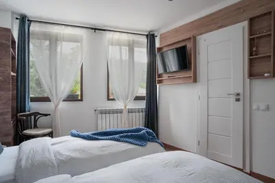 a bedroom with two beds and a window at Лиловата Къща in Kalofer