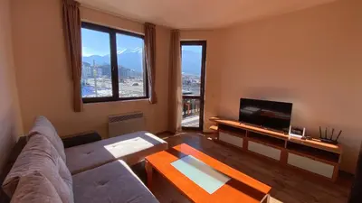 a living room with a couch and a tv at Snow Lodge Mountain view in Bansko