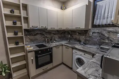 a kitchen with white cabinets and a washer and dryer at Никонел in Oborishte