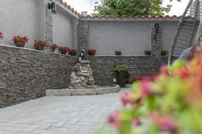 a dog sitting on a brick wall with a fountain at Никонел in Oborishte