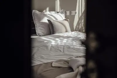 a bedroom with a bed with white sheets and pillows at Къща за гости Давиос in Sapareva Banya