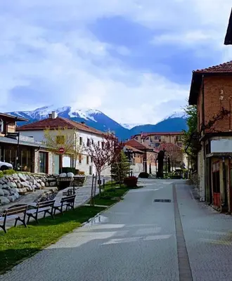 a street in a town with a mountain in the background at Cozy studio with balcony and incl SPA in 4-star hotel Saint Ivan Rilski , Bansko in Bansko