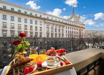 a tray of breakfast food on a balcony with a building at Free Parking And Parliament Is 1 Step Away in Sofia