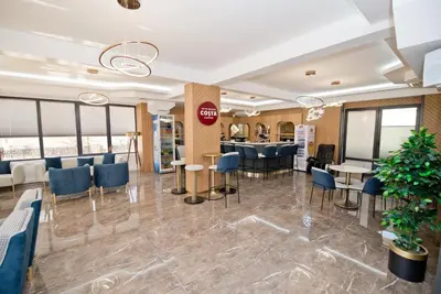 a lobby of a restaurant with blue chairs and tables at СПА Хотел Романтика in Sarnitsa