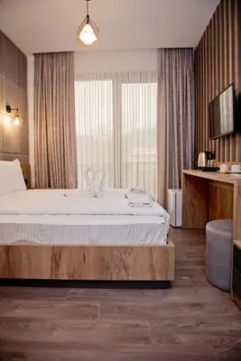 a bedroom with a bed and a large window at СПА Хотел Романтика in Sarnitsa