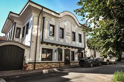 a white building with cars parked in front of it at Едно Време in Karlovo