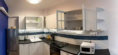 a kitchen with white cabinets and a black counter top at Sofia Apartment with Free Parking in Sofia