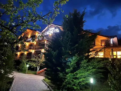 a hotel at night with a tree in front of it at ArdoVel Park Hotel in Velingrad