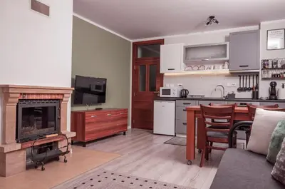 a living room with a kitchen and a table with a fireplace at Утро без Аларма, Смолянски езера. Alarm free Morning Smolyan lakes in Smolyan