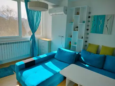 a living room with a blue couch and a window at Alinik Apartment in Sofia