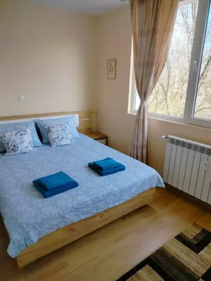 a bedroom with a bed with blue sheets and a window at Alinik Apartment in Sofia