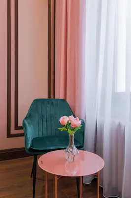 a green chair and a vase with pink flowers on a table at Charming Pastel 1BD Flat in The Heart of Sofia by Flat Mаnager in Sofia