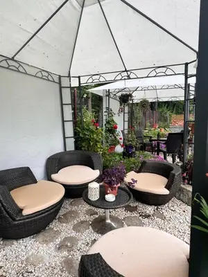 a patio with wicker chairs and tables under a tent at Villa Janet in Dolna Banya