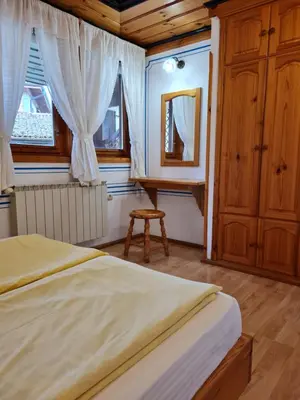 a bedroom with a bed and a mirror and a chair at Астра къща за гости in Koprivshtitsa