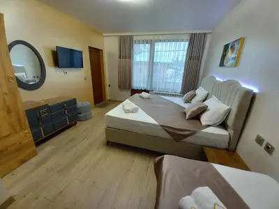 a hotel room with two beds and a mirror at ЕЛЕГАНС къща за гости in Dospat