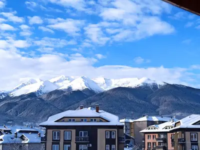 a city with snow covered mountains in the background at VV Apartment Bansko in Bansko