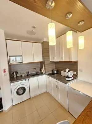 a kitchen with white cabinets and a washing machine at Bansko Private VIP Apartment in Bansko