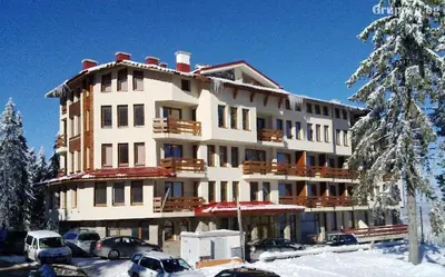 a large building with cars parked in the snow at Rositsa 28 in Pamporovo