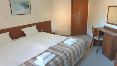 a bedroom with a bed and a desk with towels on it at Rositsa 28 in Pamporovo