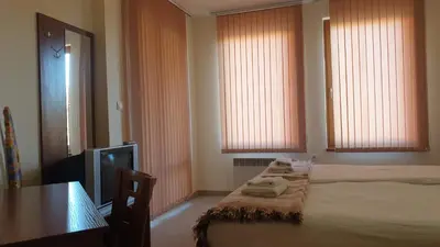 a bedroom with two beds and a table and a television at Rositsa 28 in Pamporovo