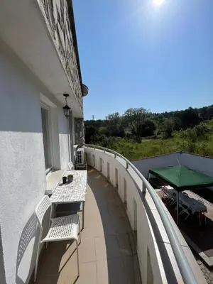 a balcony with benches and a table and a green umbrella at Къща за гости Замък Никола in Shtarkelovo Gnezdo