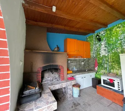 a kitchen with a brick fireplace in the middle at Къща за гости Замък Никола in Shtarkelovo Gnezdo