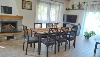a dining room with a table and chairs and a fireplace at Тиловите къщи in Ribarica
