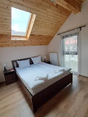 a bedroom with a large bed with a large window at Тиловите къщи in Ribarica