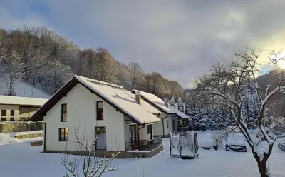 a white house with snow on the roof at Тиловите къщи in Ribarica
