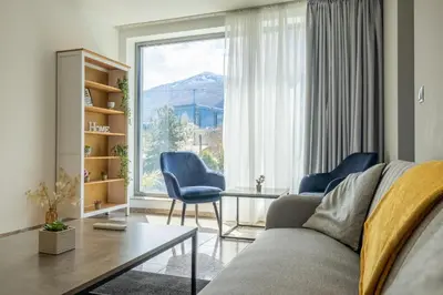 a living room with a couch and a table and a large window at Modern Apartment 3 with Parking next to Bulgaria Mall in Sofia