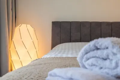 a close up of a bed with a blanket and a lamp at Modern Apartment 3 with Parking next to Bulgaria Mall in Sofia