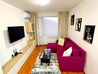 a living room with a purple couch and a tv at VIP Apartment Belvedere Club in Bansko