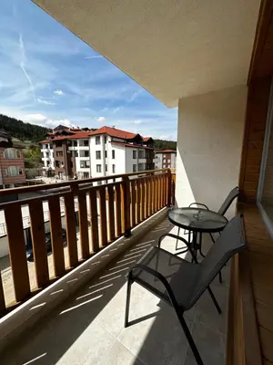 a table and a chair on a balcony with a view at Апартамент НИА in Velingrad