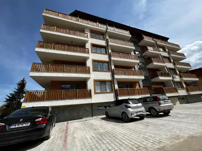two cars parked in a parking lot in front of a building at Апартамент НИА in Velingrad